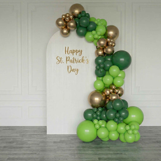 Balloon arch with green and gold balloons and 'Happy St. Patrick's Day' text on a white board.