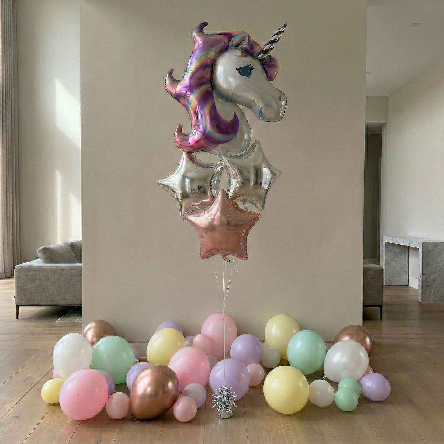Unicorn-shaped balloon with colorful balloons on a wooden floor.