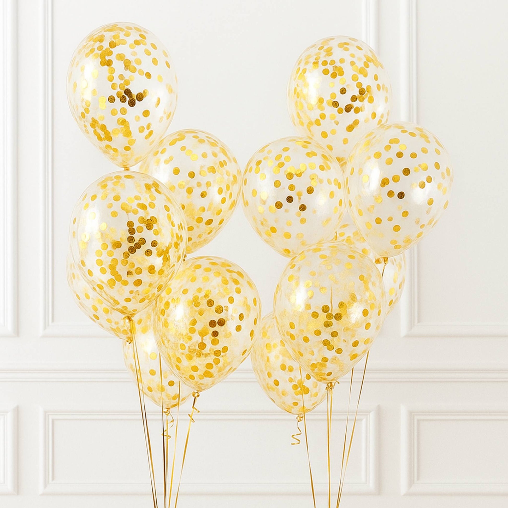 Gold confetti balloons against a white paneled wall