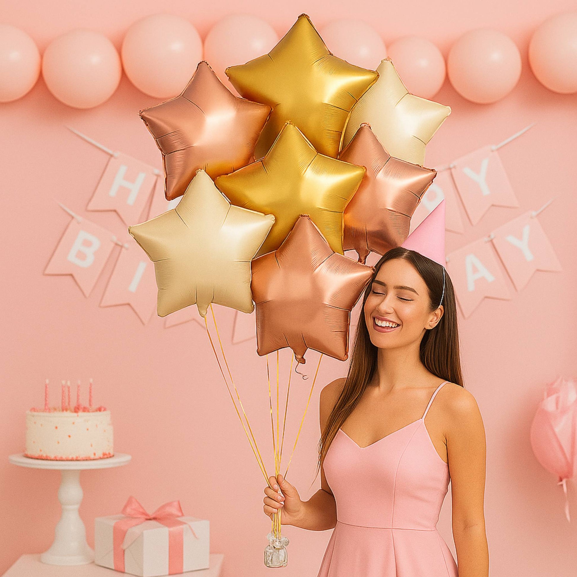 Woman holding star-shaped balloons in front of a pink birthday background with a cake and gift box.