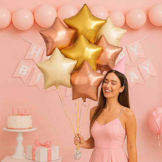 Woman holding star-shaped balloons in front of a pink birthday background with a cake and gift box.