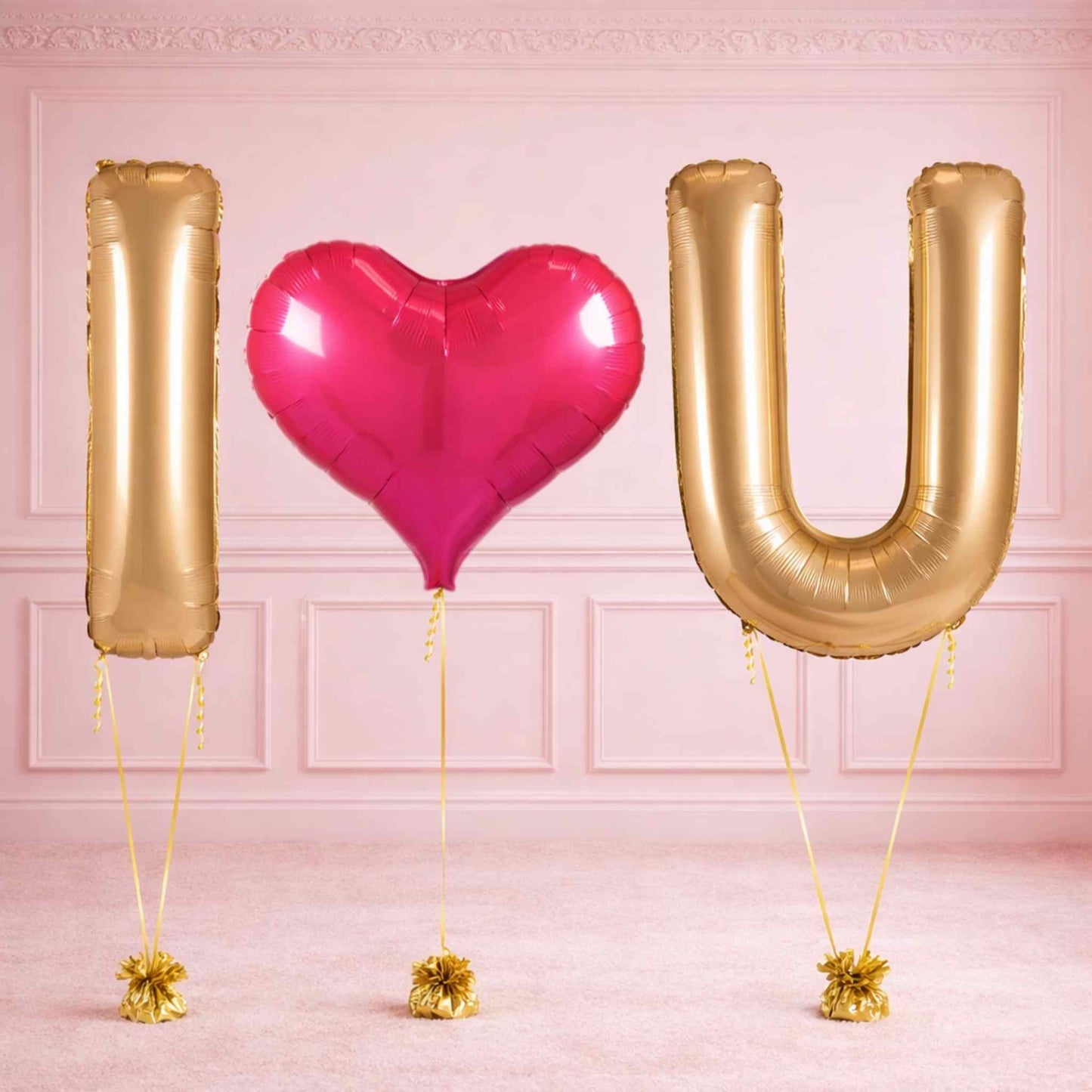 Gold letter balloons spelling 'I heart U' with a pink heart balloon on a pink background