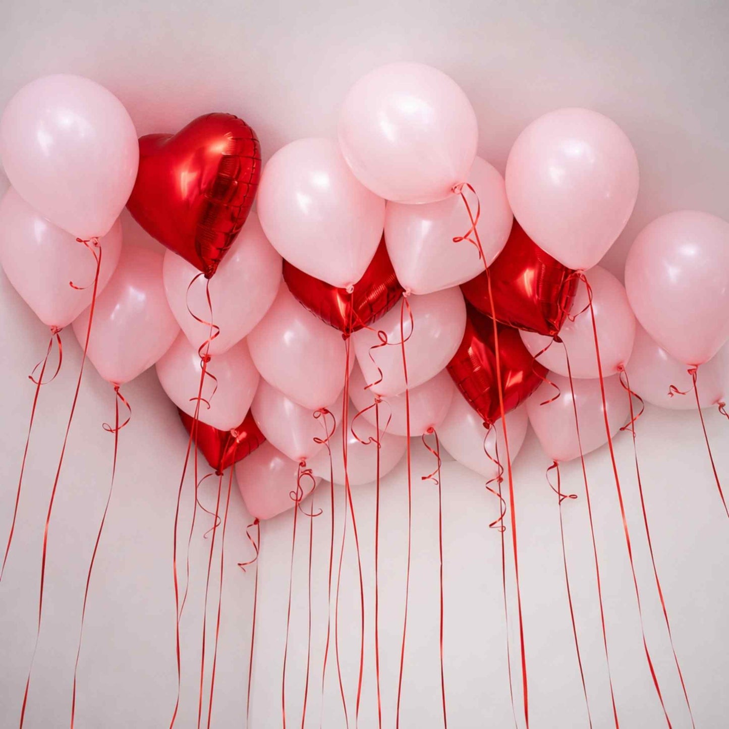 Red and pink balloons with heart shapes on a white background