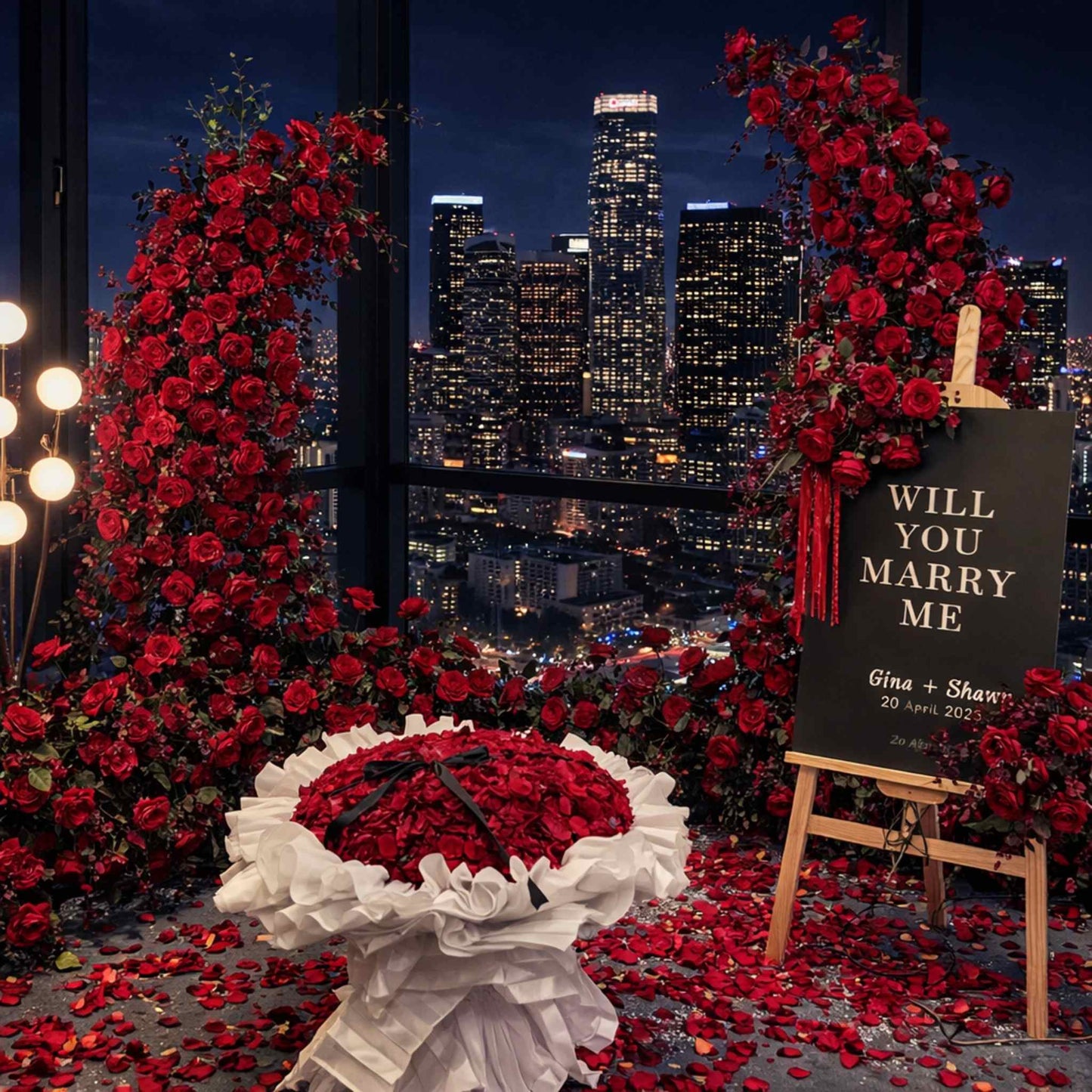Romantic proposal setup with red roses, a heart-shaped box, and 'Will You Marry Me' sign against a city skyline.