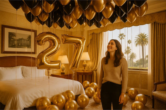 Woman standing in a room decorated with gold balloons and '27' balloons, with palm trees visible through the window.