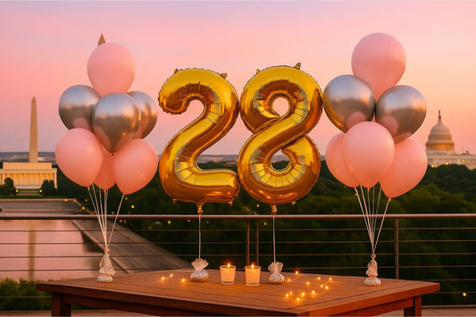 Gold number '28' balloons with pink and silver balloons on a table with a cityscape background