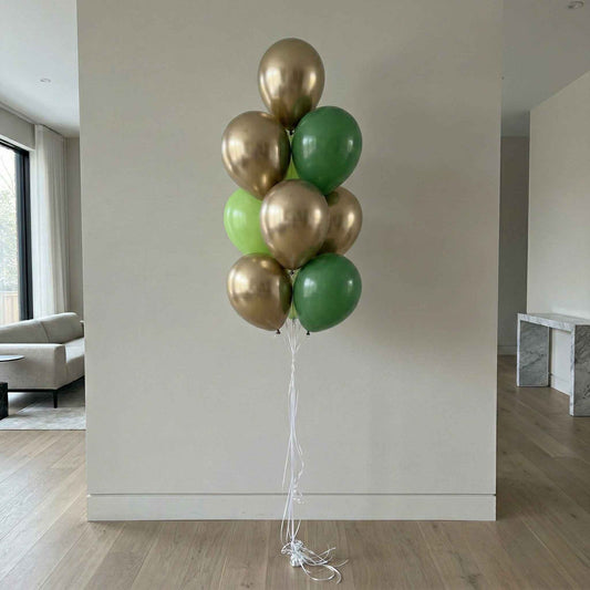 Bunch of gold and green balloons against a plain wall in a room.