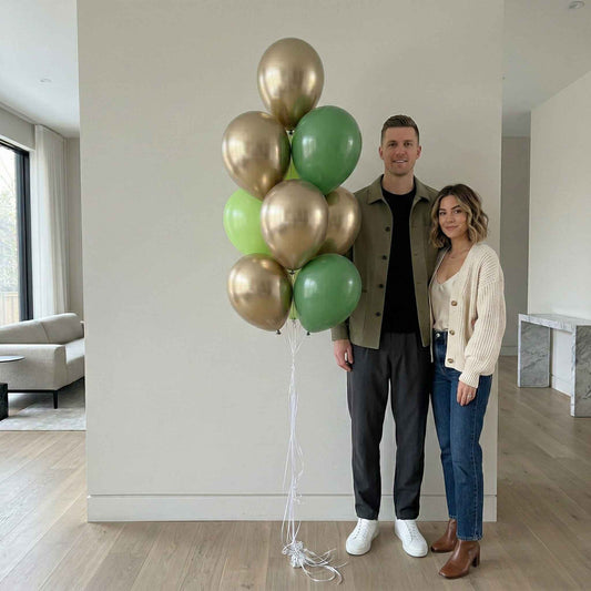 Man and woman standing in a modern living room with a large bouquet of gold and green balloons.