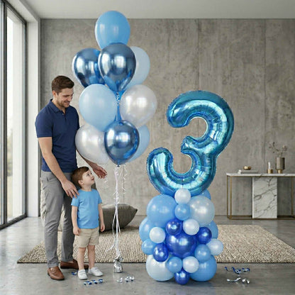 Man and child with blue, white, and silver balloons including a large number '3' in a modern room.