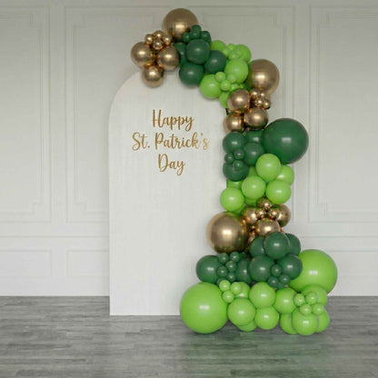 Balloon arch with green and gold balloons and 'Happy St. Patrick's Day' text on a white board.