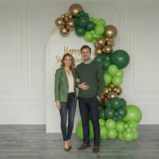 Couple posing in front of a St. Patrick's Day balloon arch with 'Happy St. Patrick's Day' text.