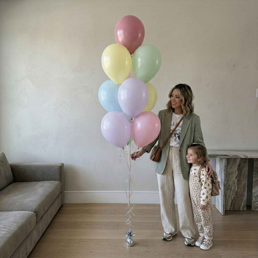 Woman and child holding a large bunch of colorful balloons indoors.