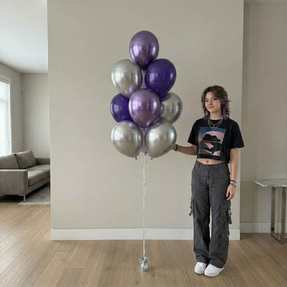 Person holding a bunch of purple and silver balloons in a room with a couch and table.
