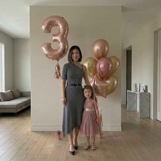 Woman and child holding rose gold balloons in a living room