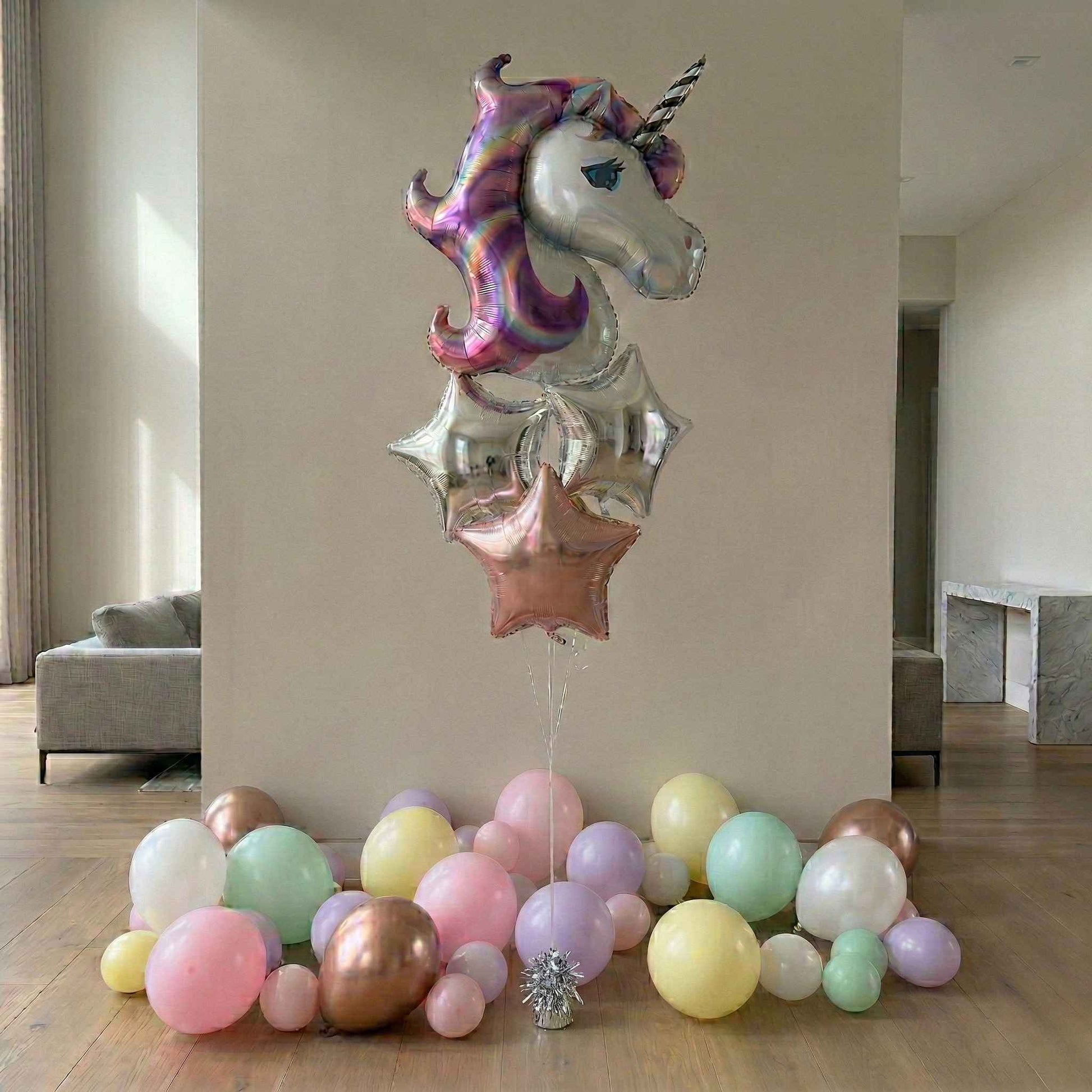 Unicorn-shaped balloon with colorful balloons on a wooden floor.