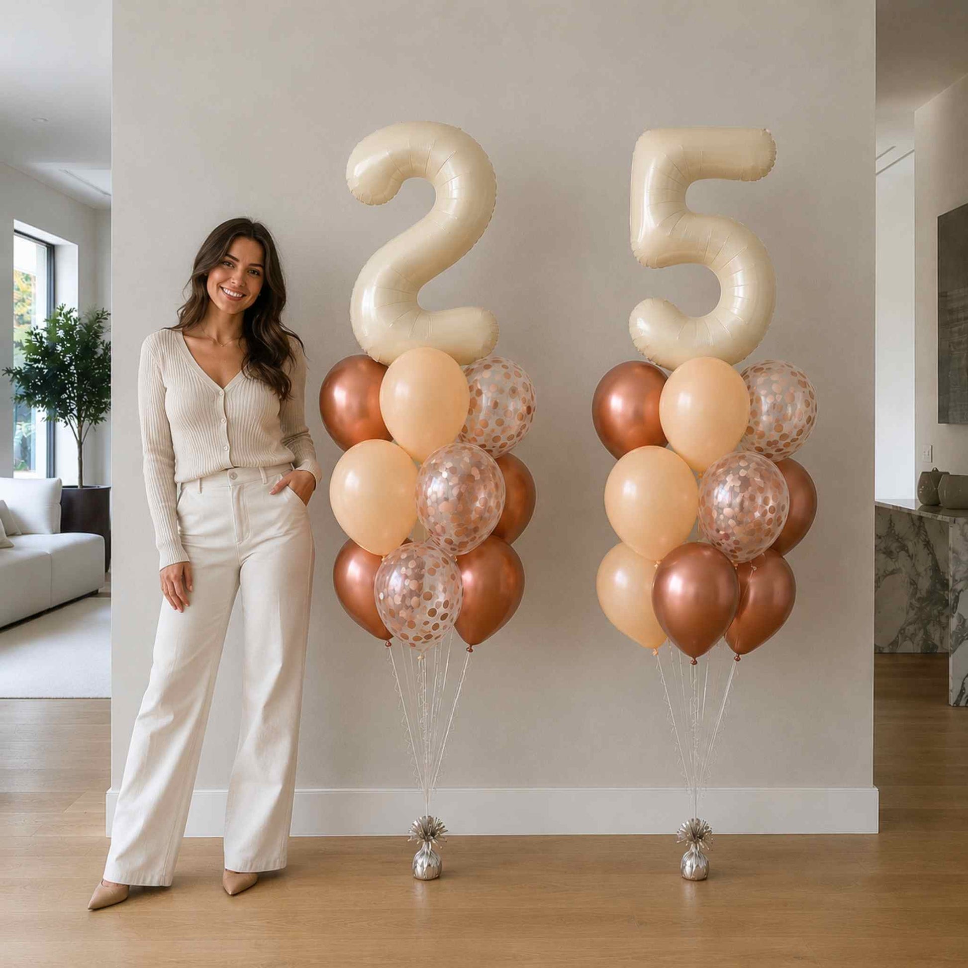 Woman standing next to large '25' balloons in a room with a couch and plant.
