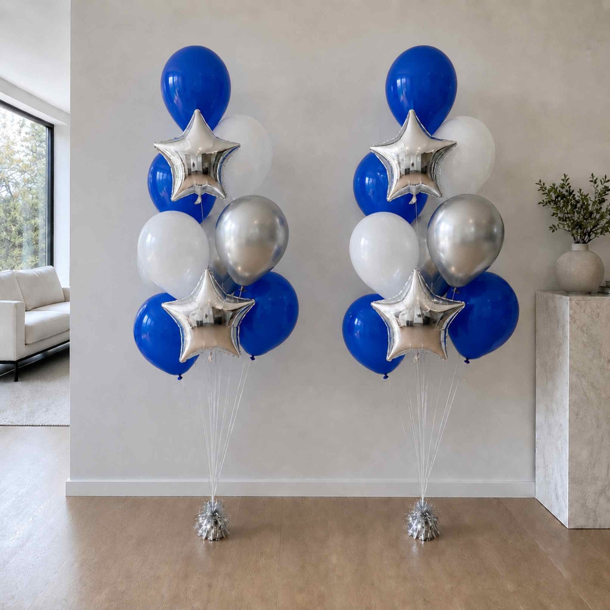 Two sets of blue, silver, and white balloons with star-shaped balloons in a room.