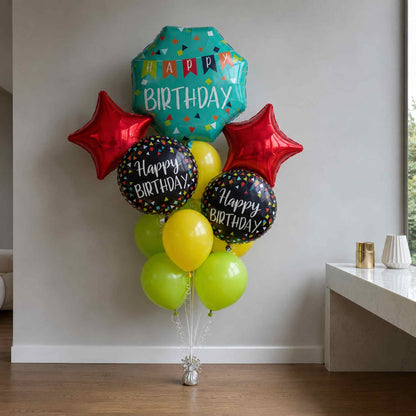 A birthday balloon bouquet with a teal confetti foil balloon reading 'HAPPY BIRTHDAY,' two red star balloons, two black round balloons with 'Happy Birthday' text, and several yellow and lime-green latex balloons, displayed indoors against a light wall.