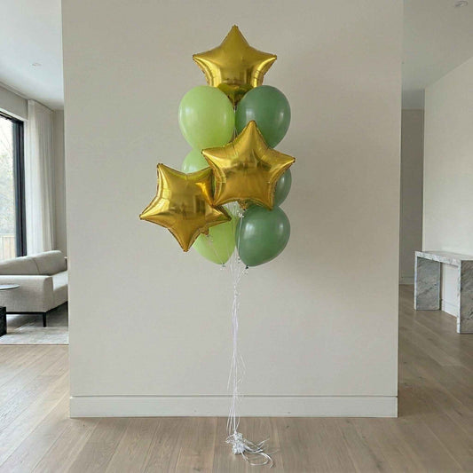 Bouquet of green and gold star balloons against a white wall in a large house