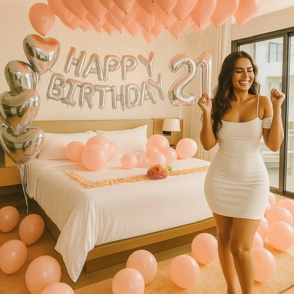 Woman in a white dress celebrating her 21st birthday in a decorated room with balloons and 'Happy Birthday' decorations.