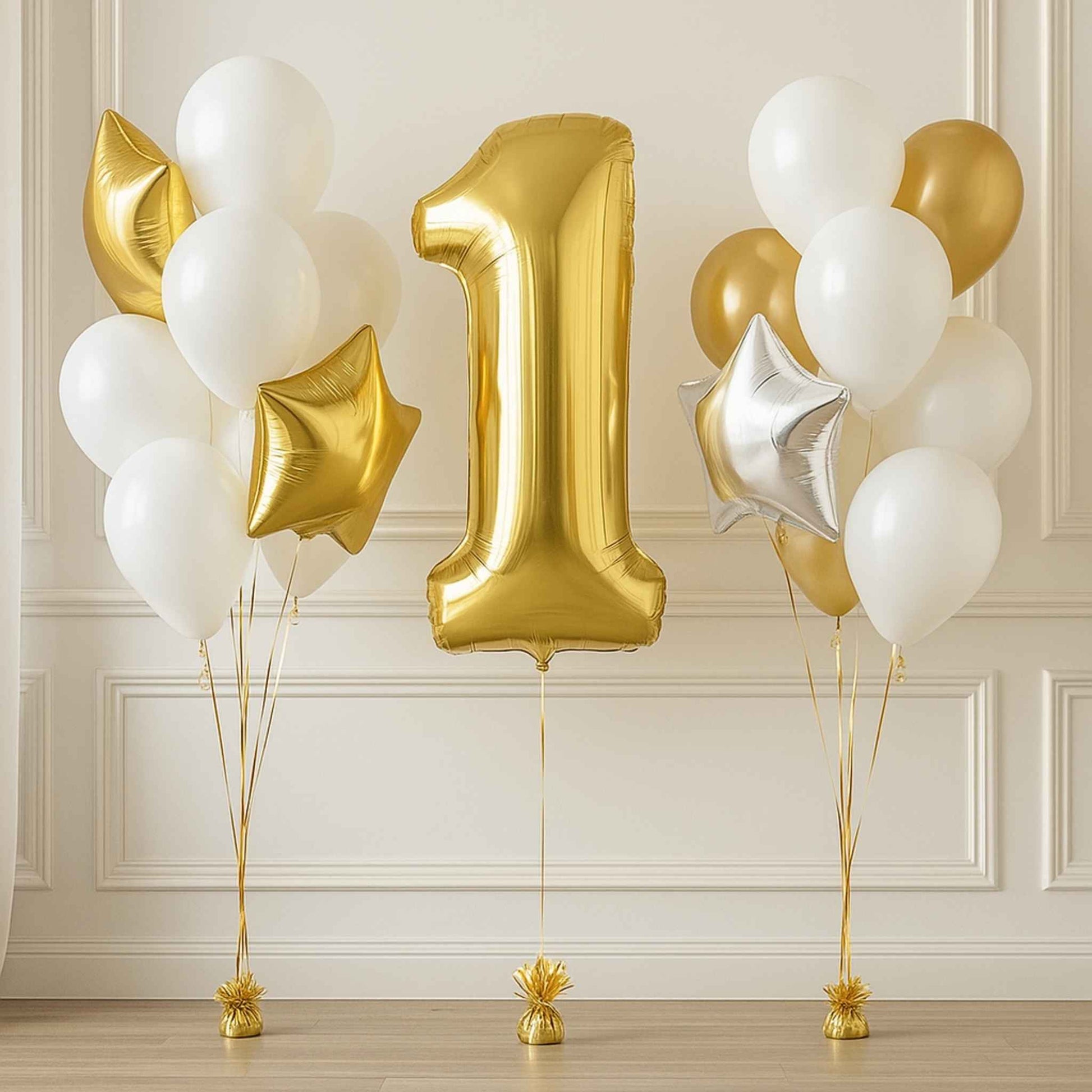 Gold number '1' balloon with white and gold balloons against a light-colored wall.