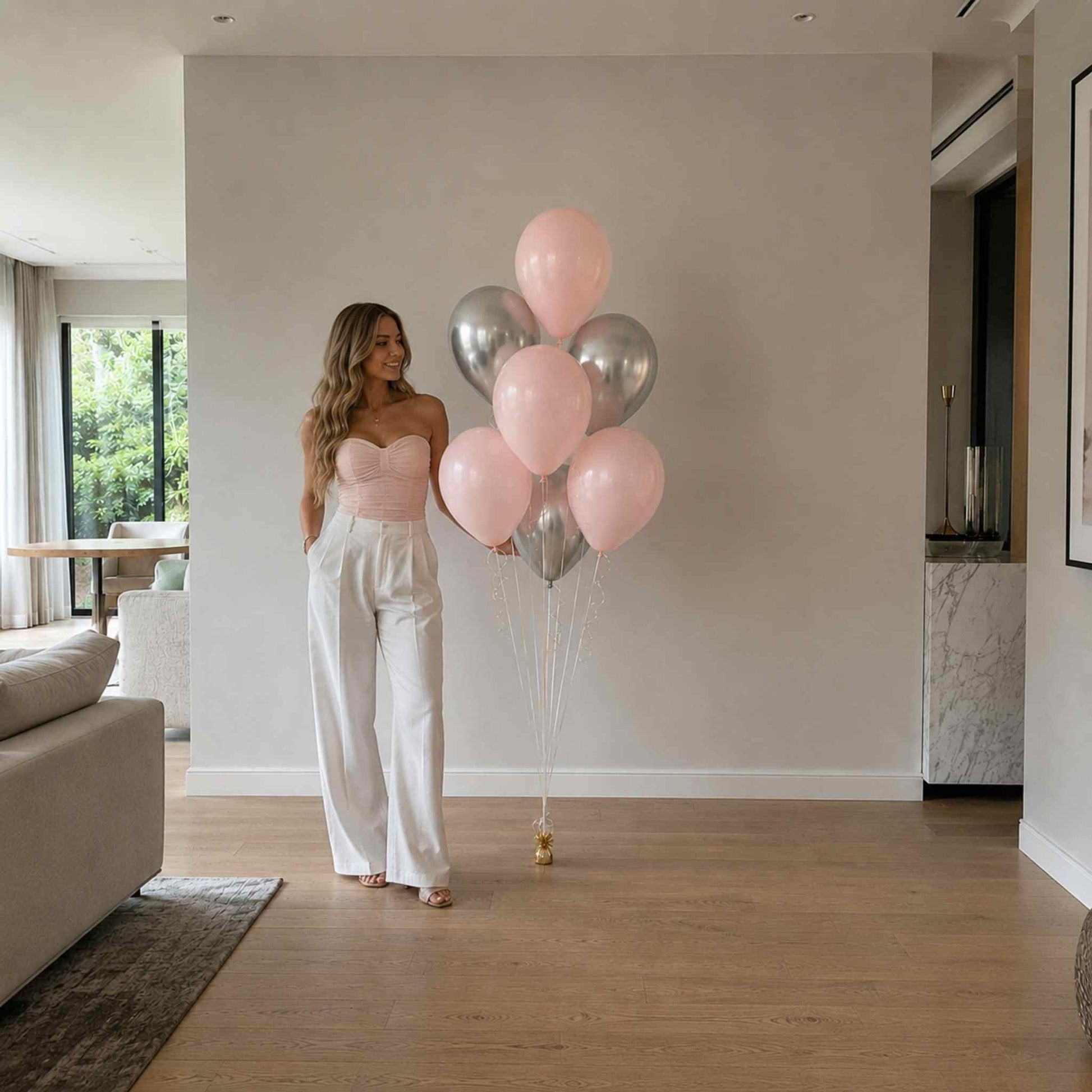 Woman holding pink and silver balloons in a modern living room.