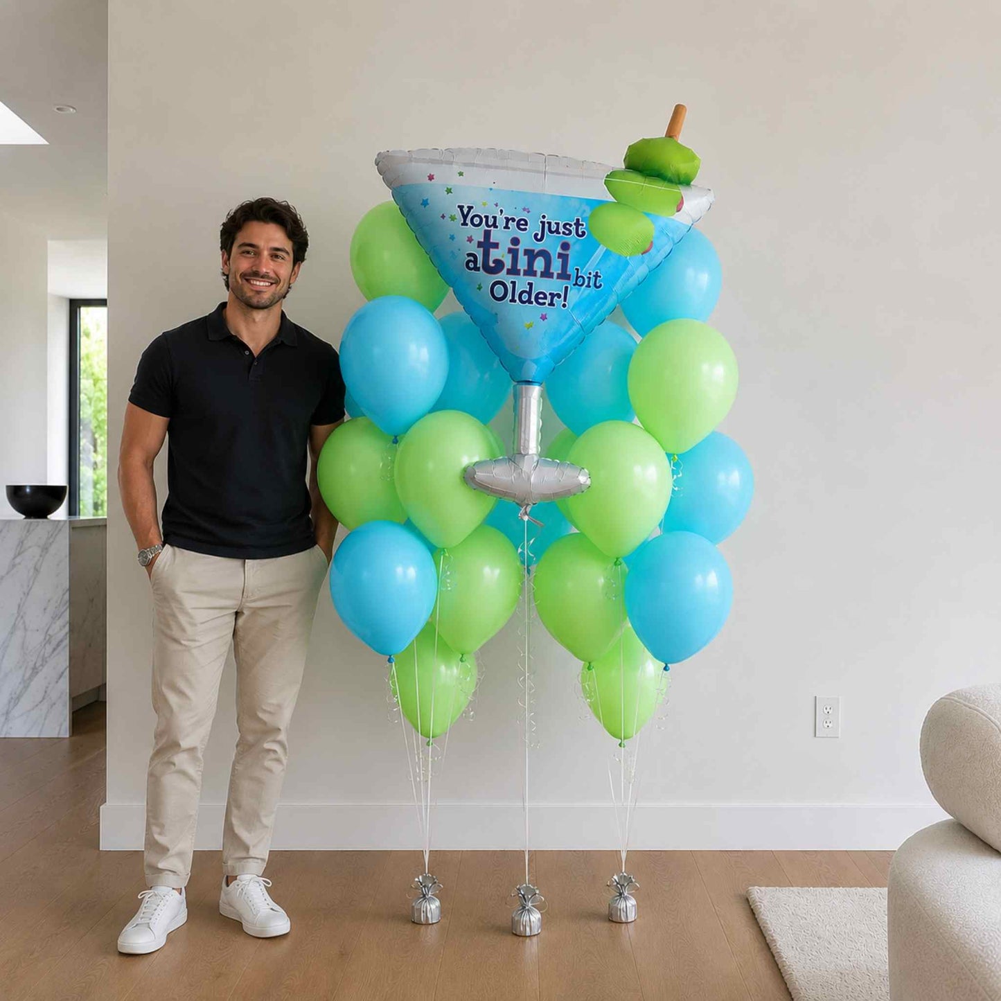 Man standing next to a large balloon decoration shaped like a martini glass with balloons.