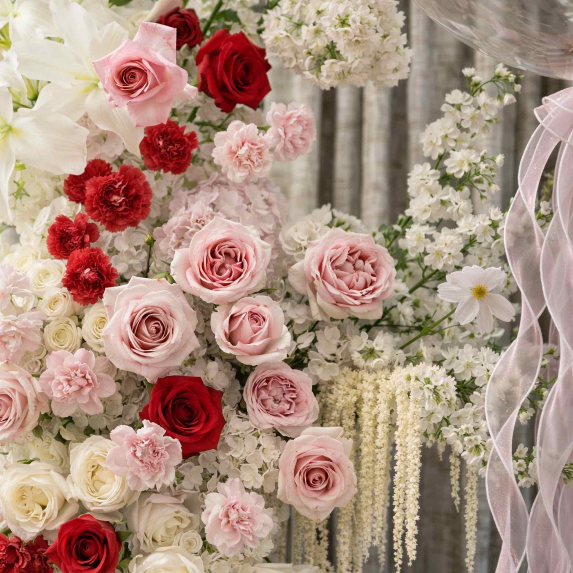 Floral arrangement with red, pink, and white roses against a blurred background