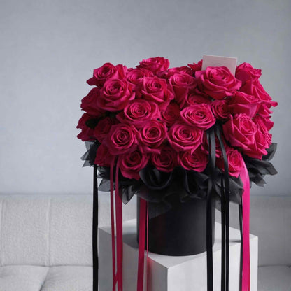 Bouquet of red roses with black ribbons on a white surface against a gray background